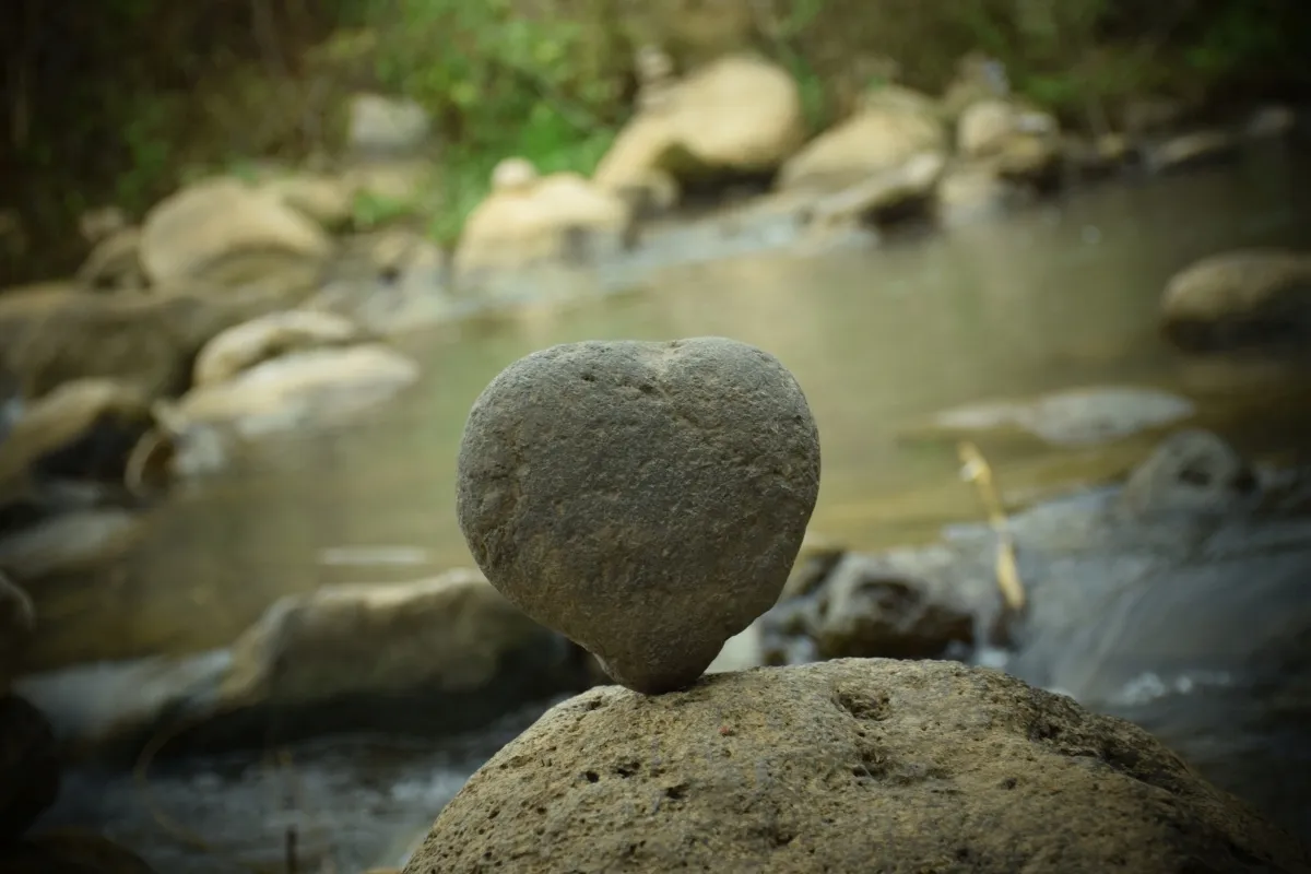 Balanced heart-shaped stone on a riverside rock
